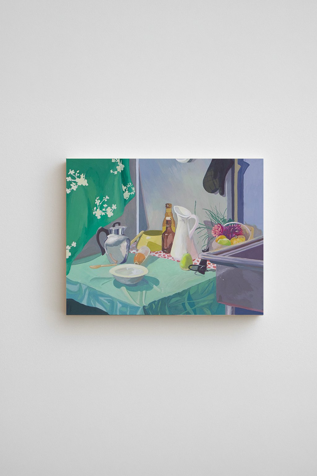 Still life painting of a metal pitcher, white ceramic pitcher, glass bottles, and a bowl on a green tablecloth, hung in a gallery